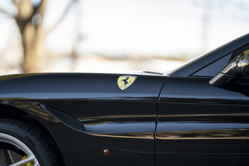 Close-up of a black Ferrari California T fender with the Prancing Horse emblem.