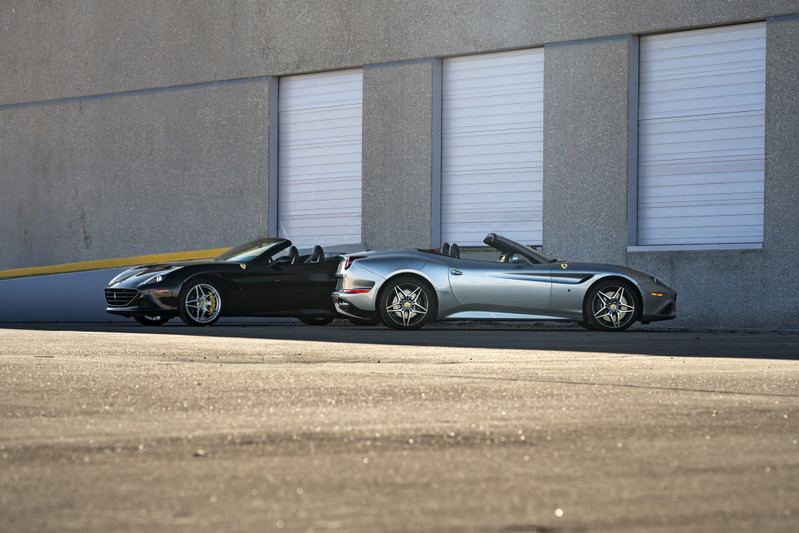 Black 2016 Ferrari California T convertible with five-spoke rims parked next to a silver one.