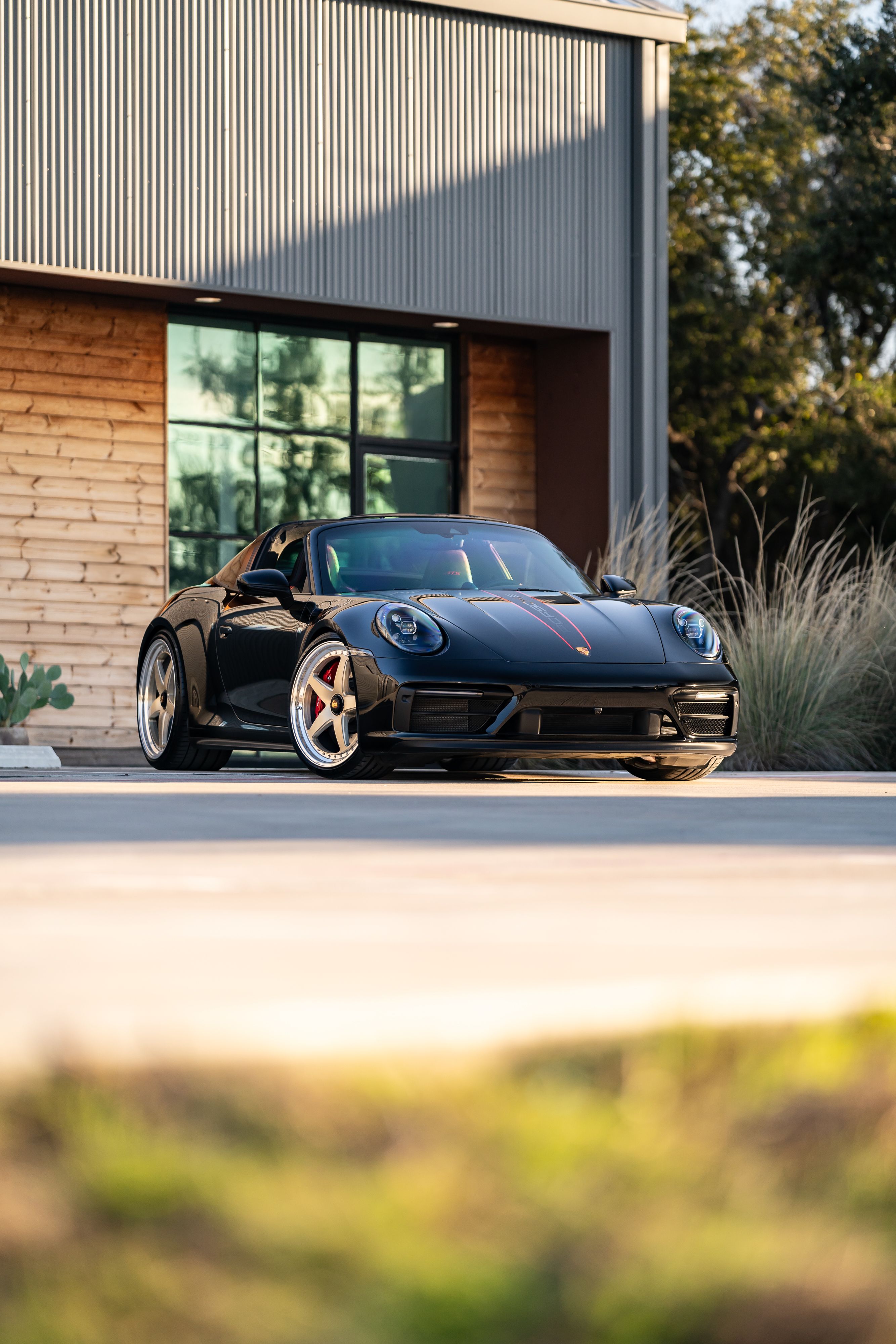 Black 2023 Porsche 911 Carrera 4 GTS with red brake calipers and a sport exhaust.