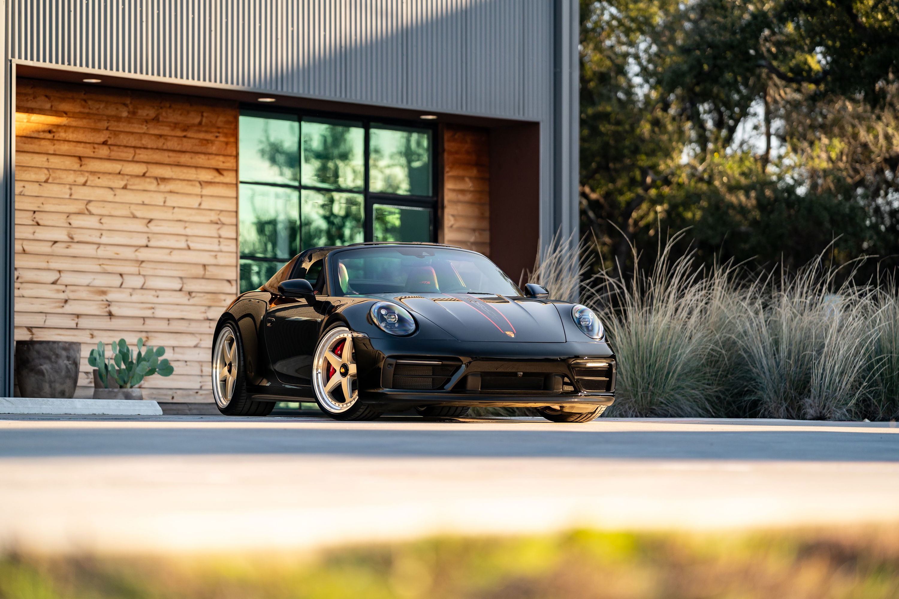 Black 2023 Porsche 911 Carrera 4 GTS with custom rims and red brake calipers.