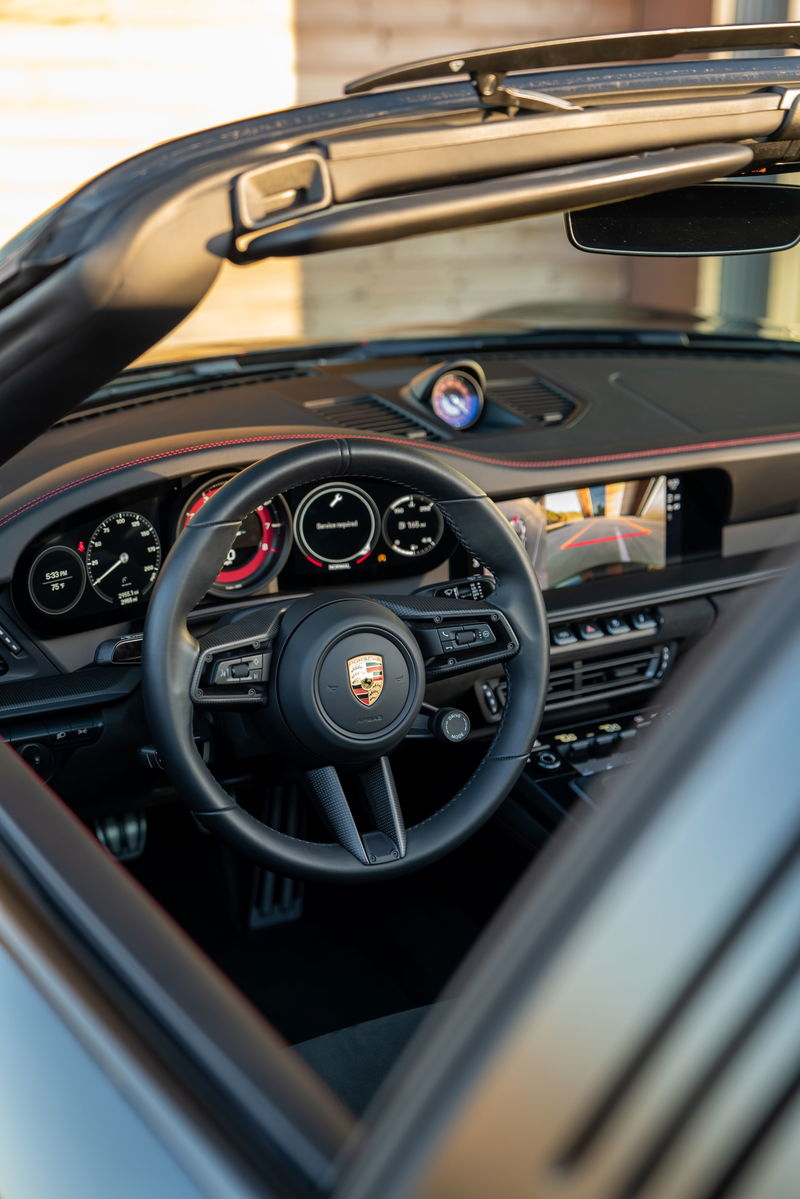 Black 2023 Porsche 911 Carrera 4 GTS interior, featuring a steering wheel, dashboard, and sport seats.