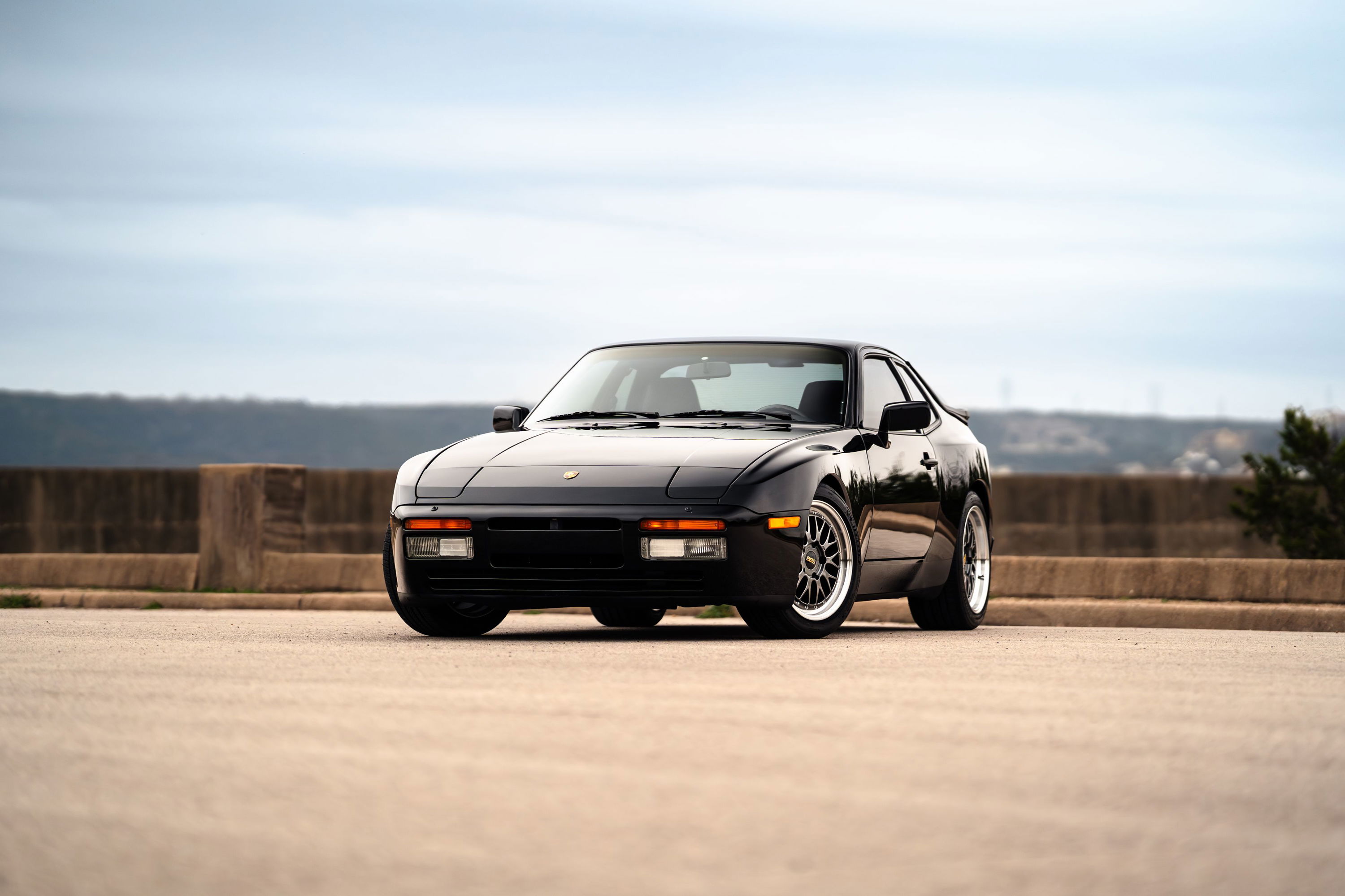 Front 3/4 view of a black 1986 Porsche 944 Turbo with silver alloy rims.