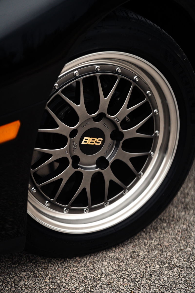 Close-up of a black 1986 Porsche 944 Turbo's BBS wheel with gold logo.