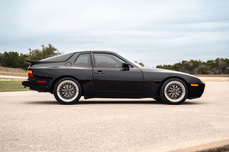 Black 1986 Porsche 944 Turbo with silver mesh rims and a rear spoiler.