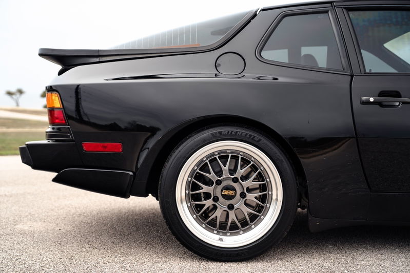 Black 1986 Porsche 944 Turbo rear quarter panel with BBS rims and a rear spoiler.