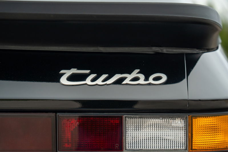 Close-up of a black 1986 Porsche 944 Turbo's rear badge and taillights.