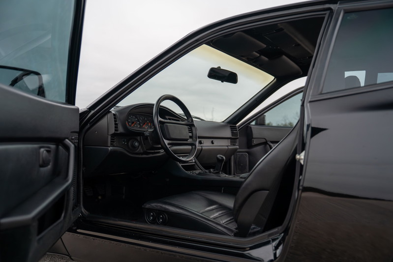 Interior view of a black 1986 Porsche 944 Turbo, showing dashboard and driver's seat.