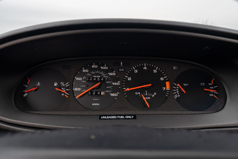 Close-up of the dashboard of a black 1986 Porsche 944 Turbo, showing the gauges and mileage.