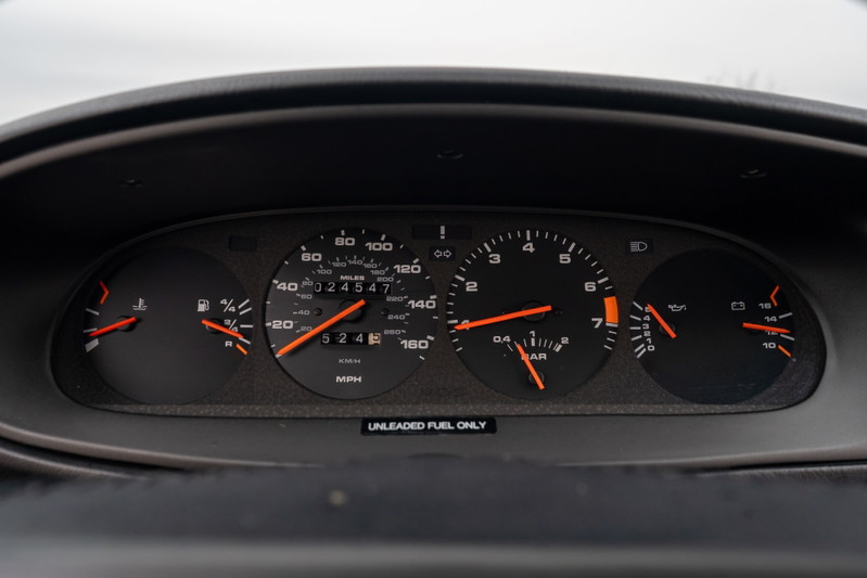 Close-up of the dashboard of a black 1986 Porsche 944 Turbo, showing the gauges and mileage.