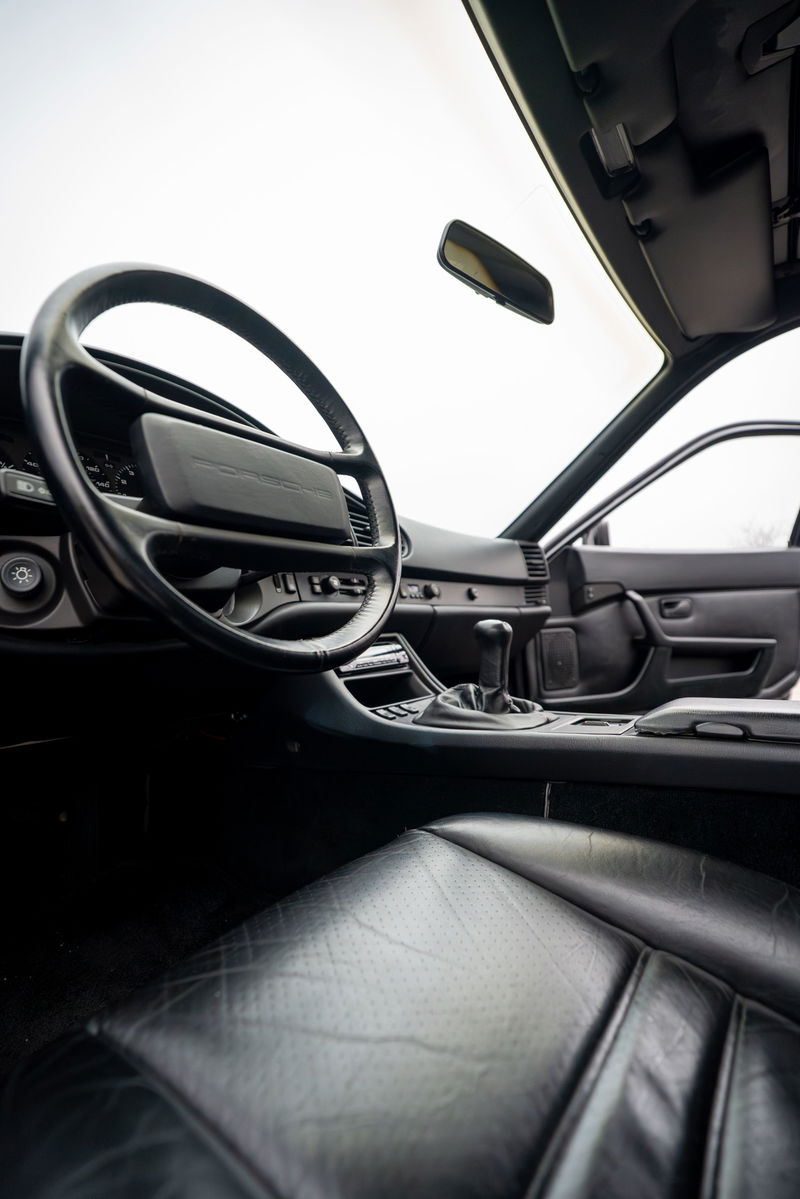 Interior of a black 1986 Porsche 944 Turbo, showing leather seats, steering wheel, and shifter.