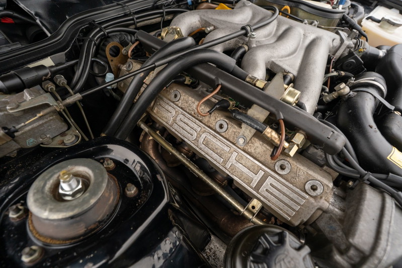 Closeup of a 1986 Porsche 944 Turbo engine bay, showing the PORSCHE embossed valve cover.