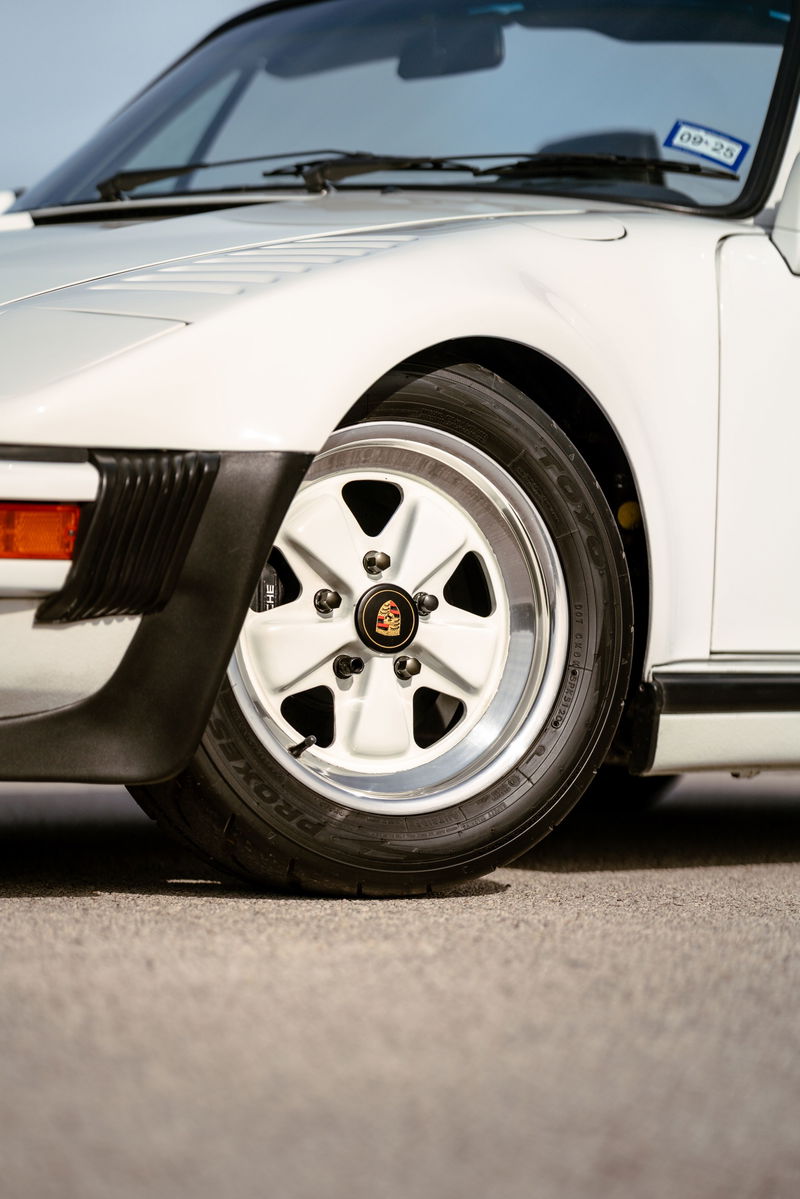White 1988 Porsche 930 Turbo Slantnose front wheel with a Fuchs rim and black trim.