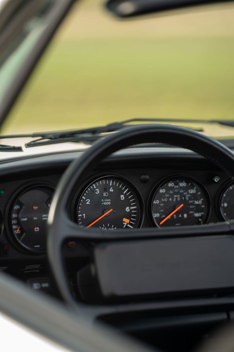 Interior of a white 1988 Porsche 930 Turbo Slantnose, showing the instrument cluster with tachometer.