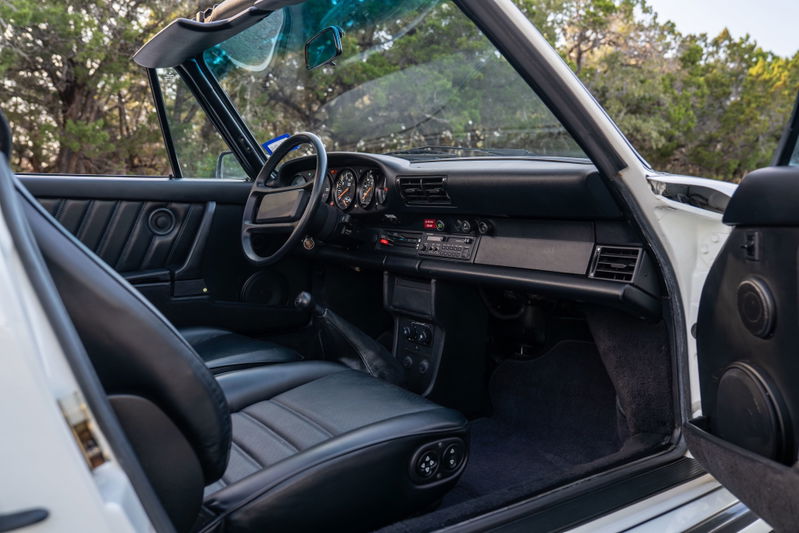 Interior view of a white 1988 Porsche 930 Turbo Slantnose convertible with black leather seats.