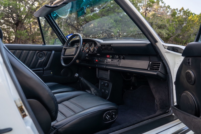 Interior view of a white 1988 Porsche 930 Turbo Slantnose convertible with black leather seats.