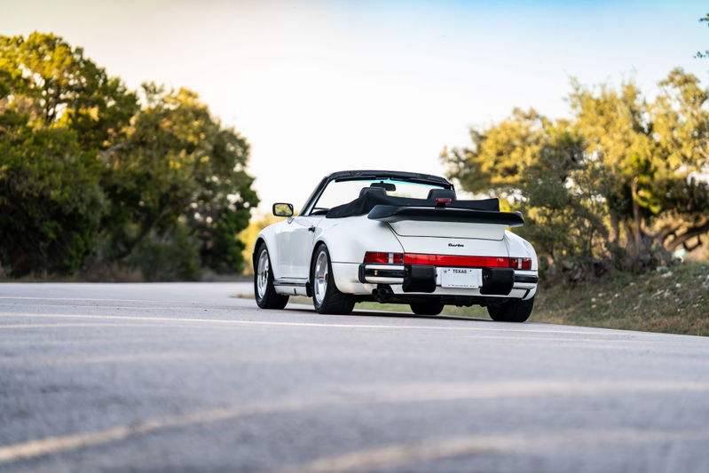 Rear view of a white 1988 Porsche 930 Turbo M505 Slantnose convertible, with classic Fuchs rims and spoiler.