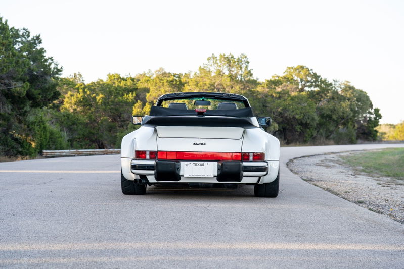 Rear view of a white 1988 Porsche 930 Turbo M505 Slantnose convertible with black trim.
