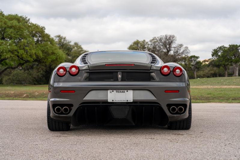 Rear view of a Grigio Silverstone 2007 Ferrari F430 6-speed with quad exhaust tips.