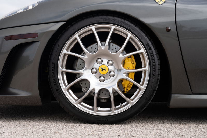 Close-up of a Grigio Silverstone 2007 Ferrari F430 with silver rims and yellow brake calipers.