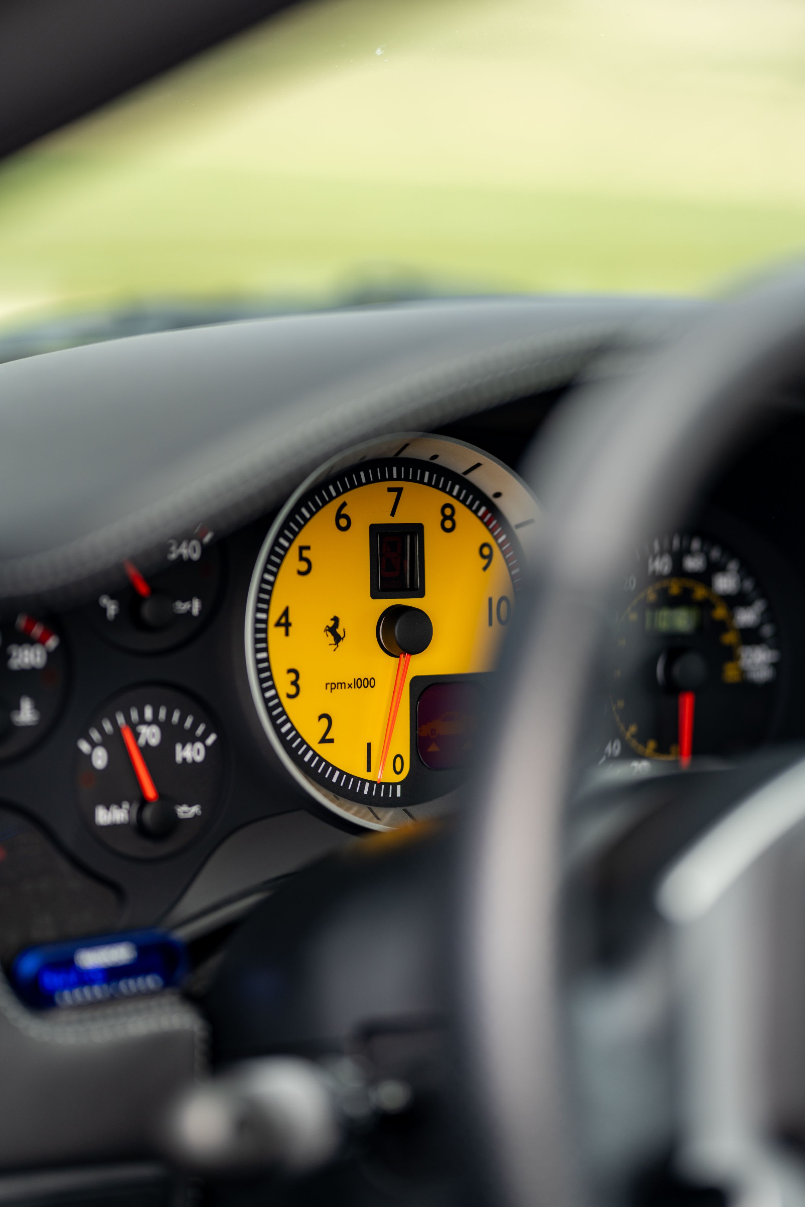 Close-up of yellow tachometer in a Grigio Silverstone 2007 Ferrari F430, showing RPM.