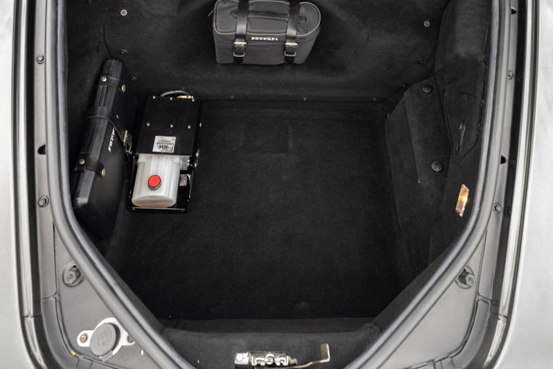 Trunk of a 2007 Ferrari F430 in Grigio Silverstone with hydraulic pump and luggage.