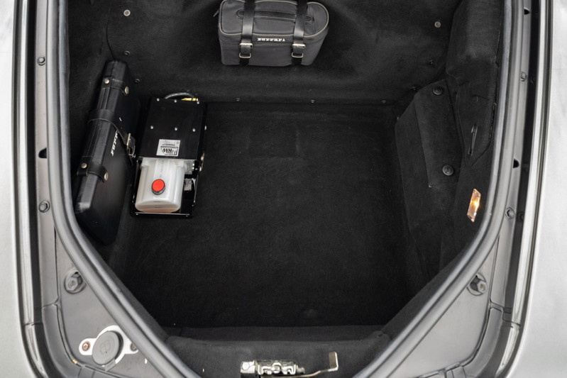 Trunk of a 2007 Ferrari F430 in Grigio Silverstone with hydraulic pump and luggage.