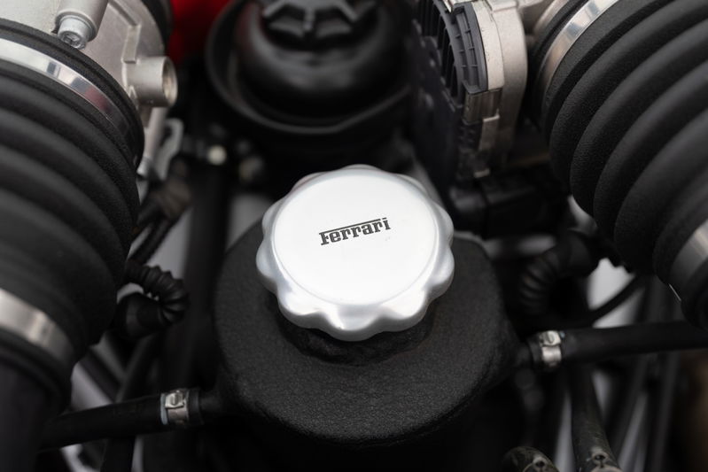 Close-up of the Ferrari F430 engine bay, highlighting the silver Ferrari-branded cap.