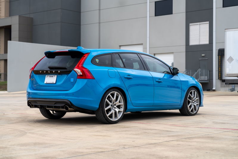 2015 Volvo V60 Polestar wagon in Rebel Blue, showing rear 3/4 view with silver alloy rims and black trim.