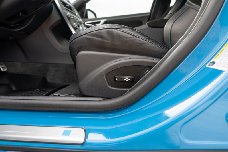 Close-up of a blue 2015 Volvo V60 Polestar's driver's seat control and interior door trim.