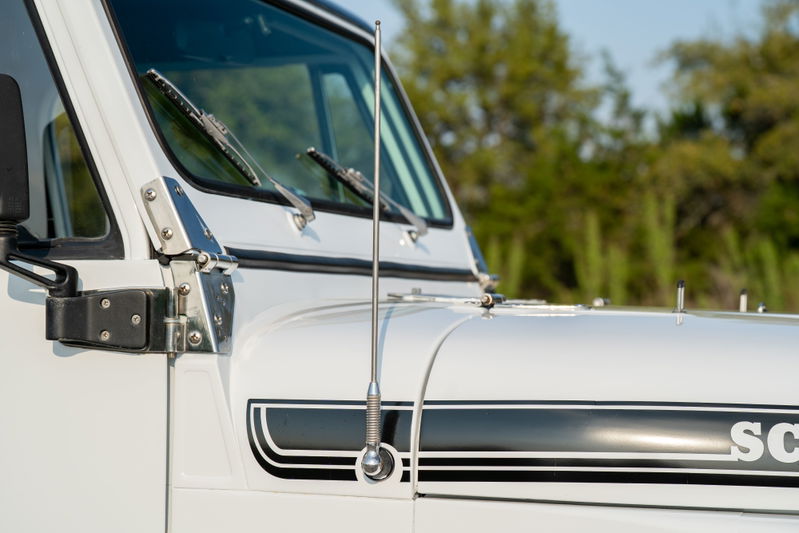 Close-up of a white 1983 Jeep Scrambler with black stripe livery and a chrome antenna.