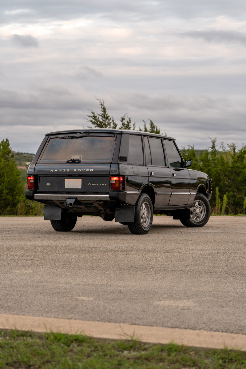 1994 black Range Rover County LWB rear 3/4 view with chrome trim and factory rims.
