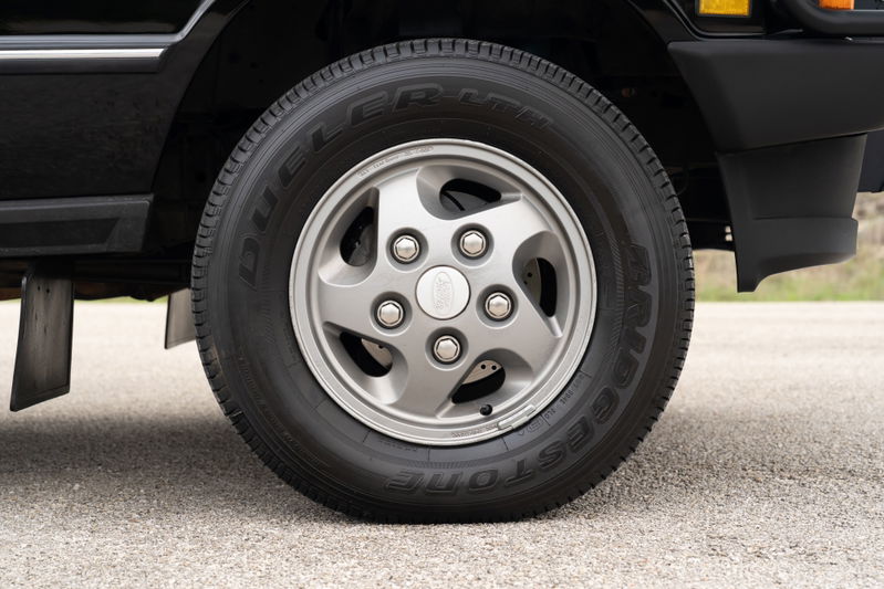 Close-up of a 1994 Range Rover County LWB's silver 5-spoke alloy rim and tire.