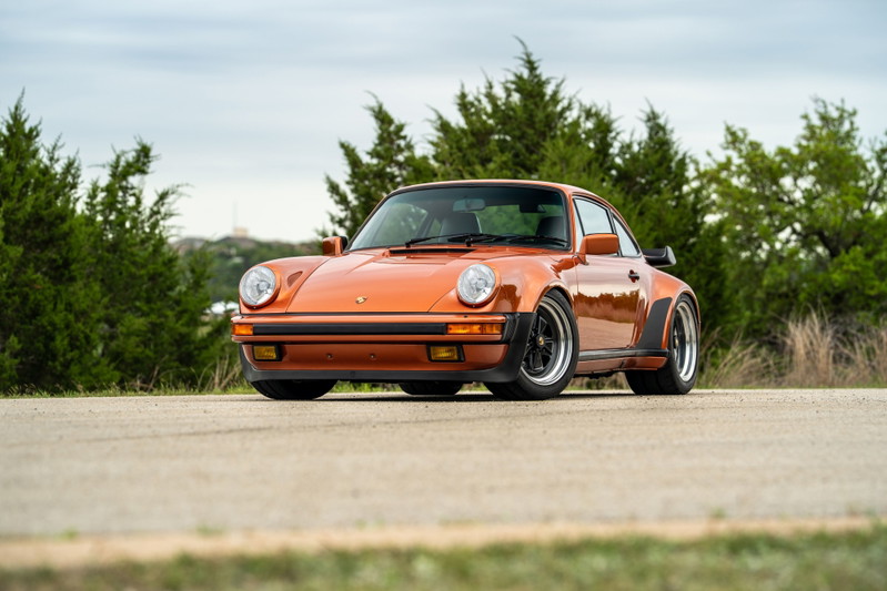 Front view of an orange metallic 1986 Porsche 930 Turbo with black trim and classic rims.