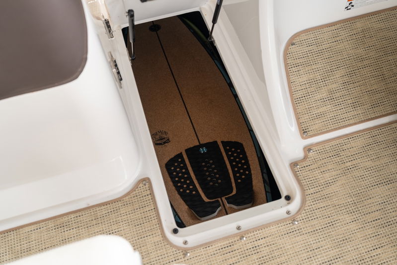 Cobalt R7 Surf boat with a wakeboard stored in a bow locker, featuring a cork deck.