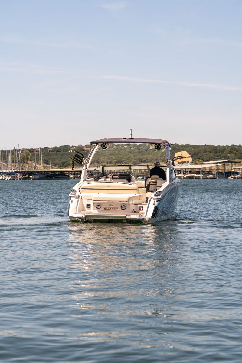 2025 Cobalt R7 Surf wake boat with blue accents and a silver hull, navigating calm waters.