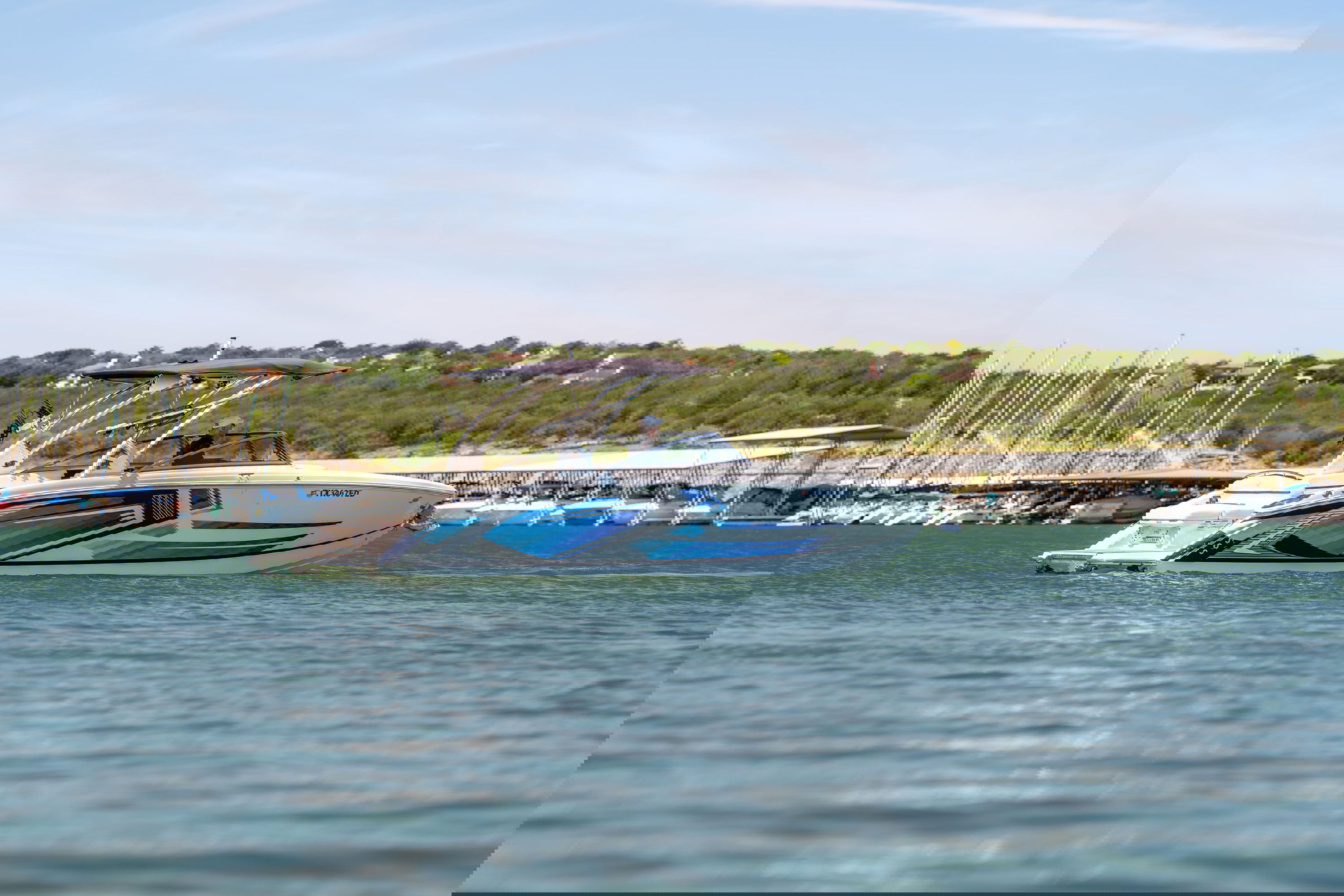 2025 Cobalt R7 Surf boat with a striking blue and white livery design on a calm lake.