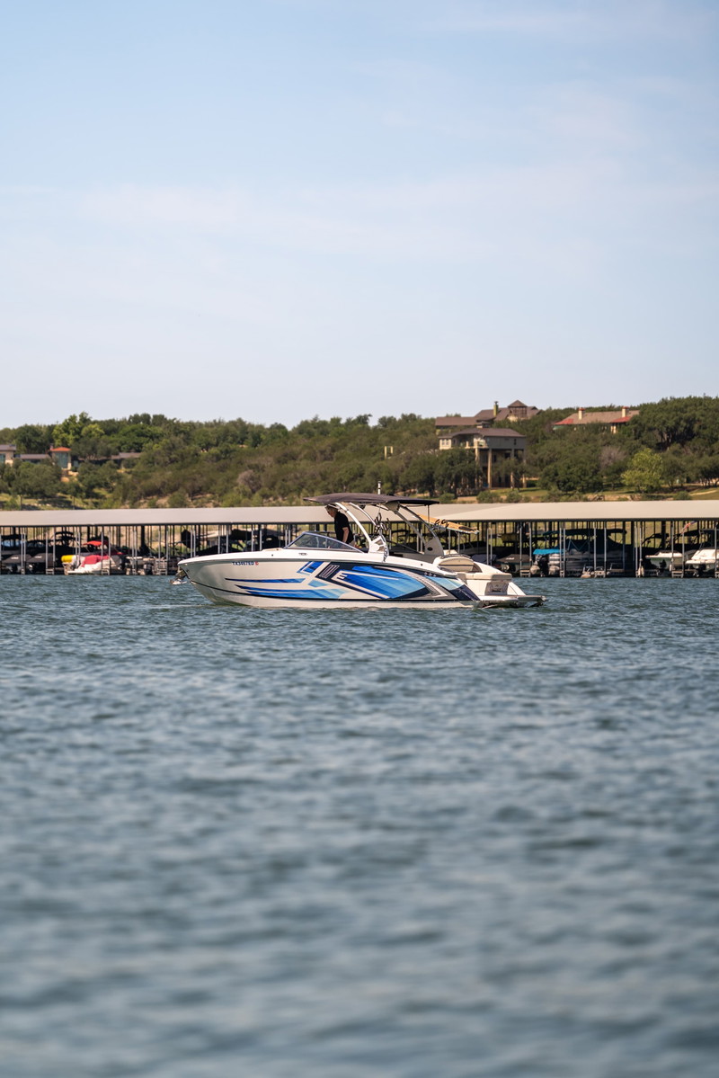 White Cobalt R7 Surf boat with blue and silver livery, docked at a marina on a sunny day.