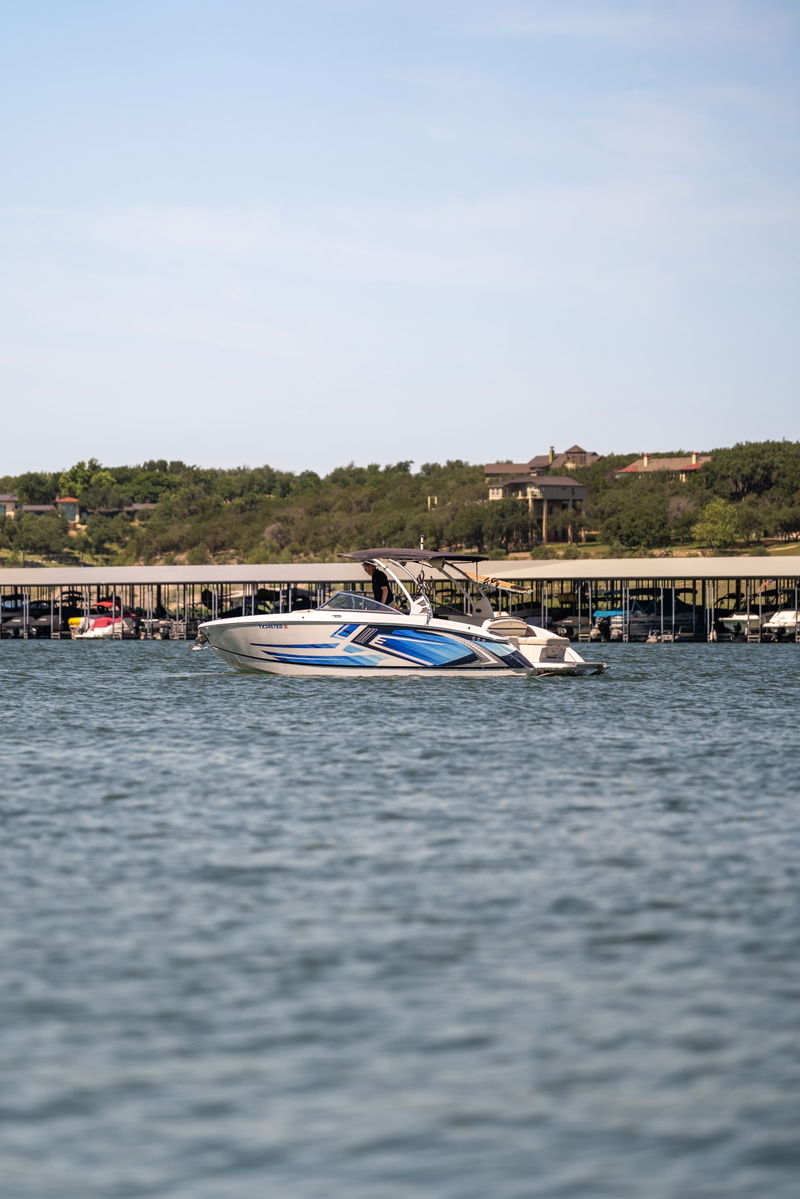 White Cobalt R7 Surf boat with blue and silver livery, docked at a marina on a sunny day.