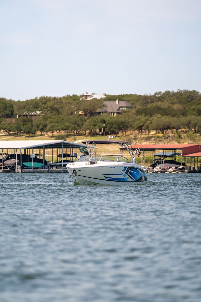 White 2018 Cobalt R7 Surf boat with blue accents, parked at a dock on a sunny day.
