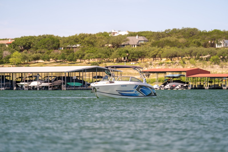 White Cobalt R7 Surf boat with blue graphic livery and bimini top on blue water.