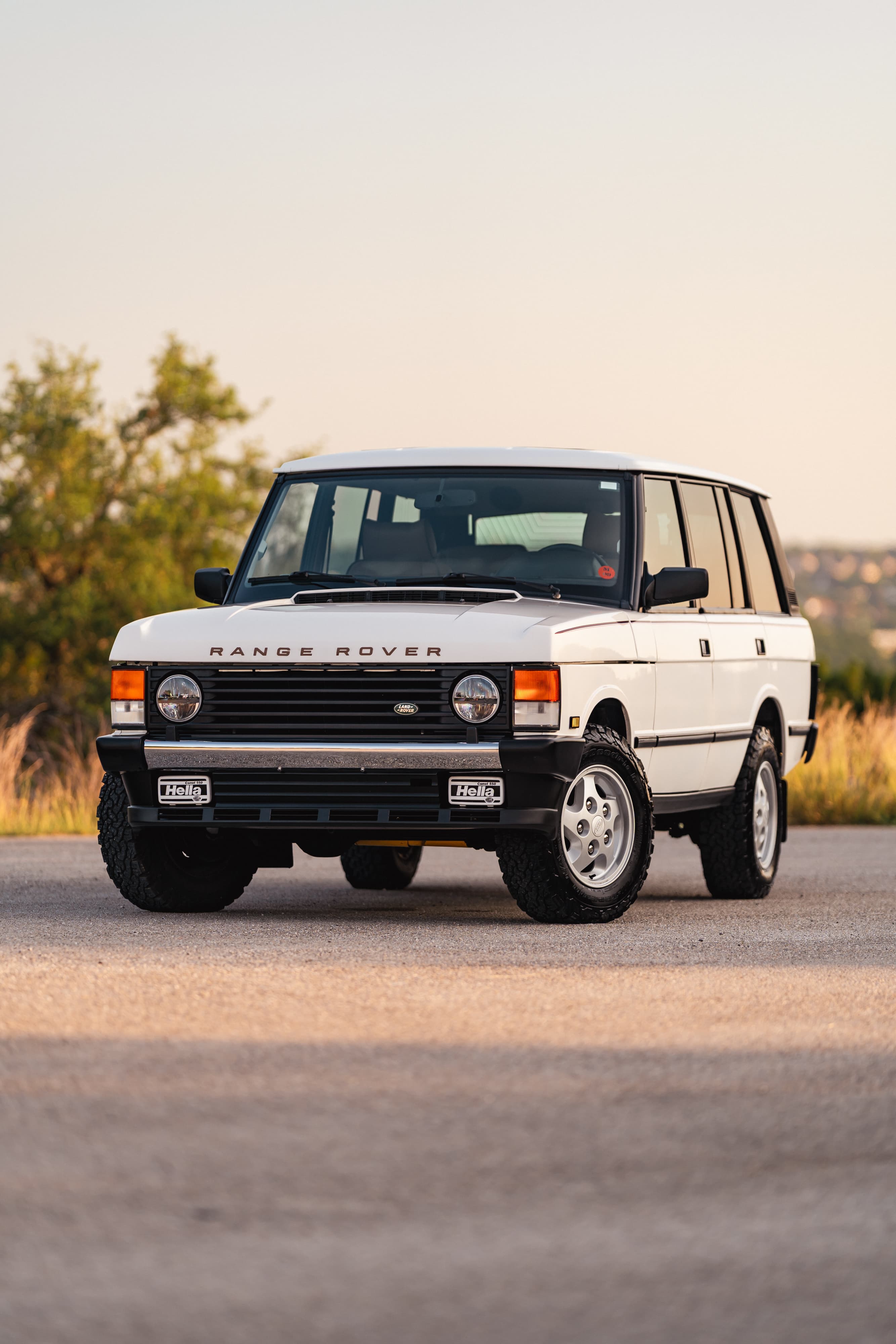 Front view of a white 1995 Range Rover County with Hella lights and silver rims.