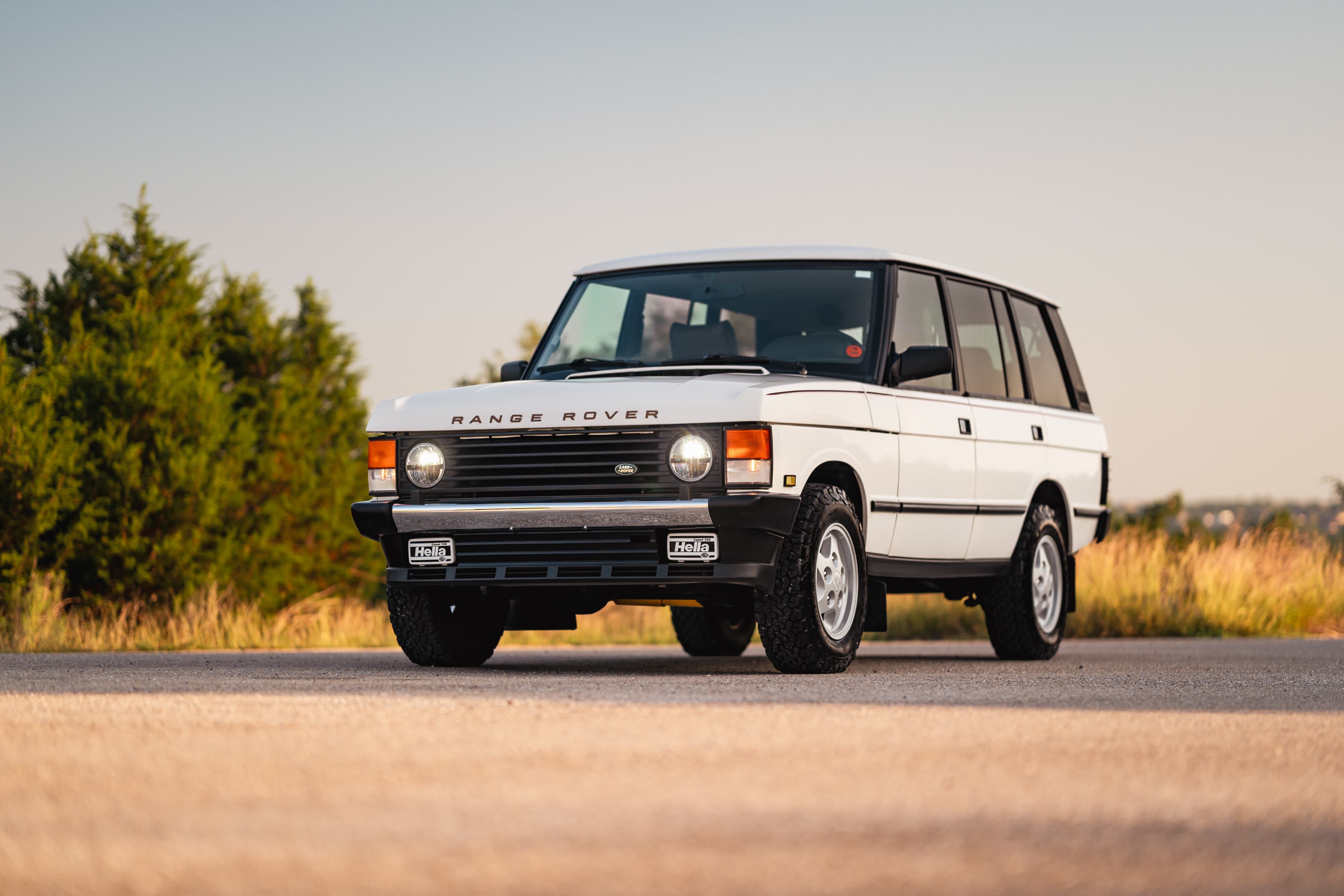 White 1995 Land Rover Range Rover County on road with trees.