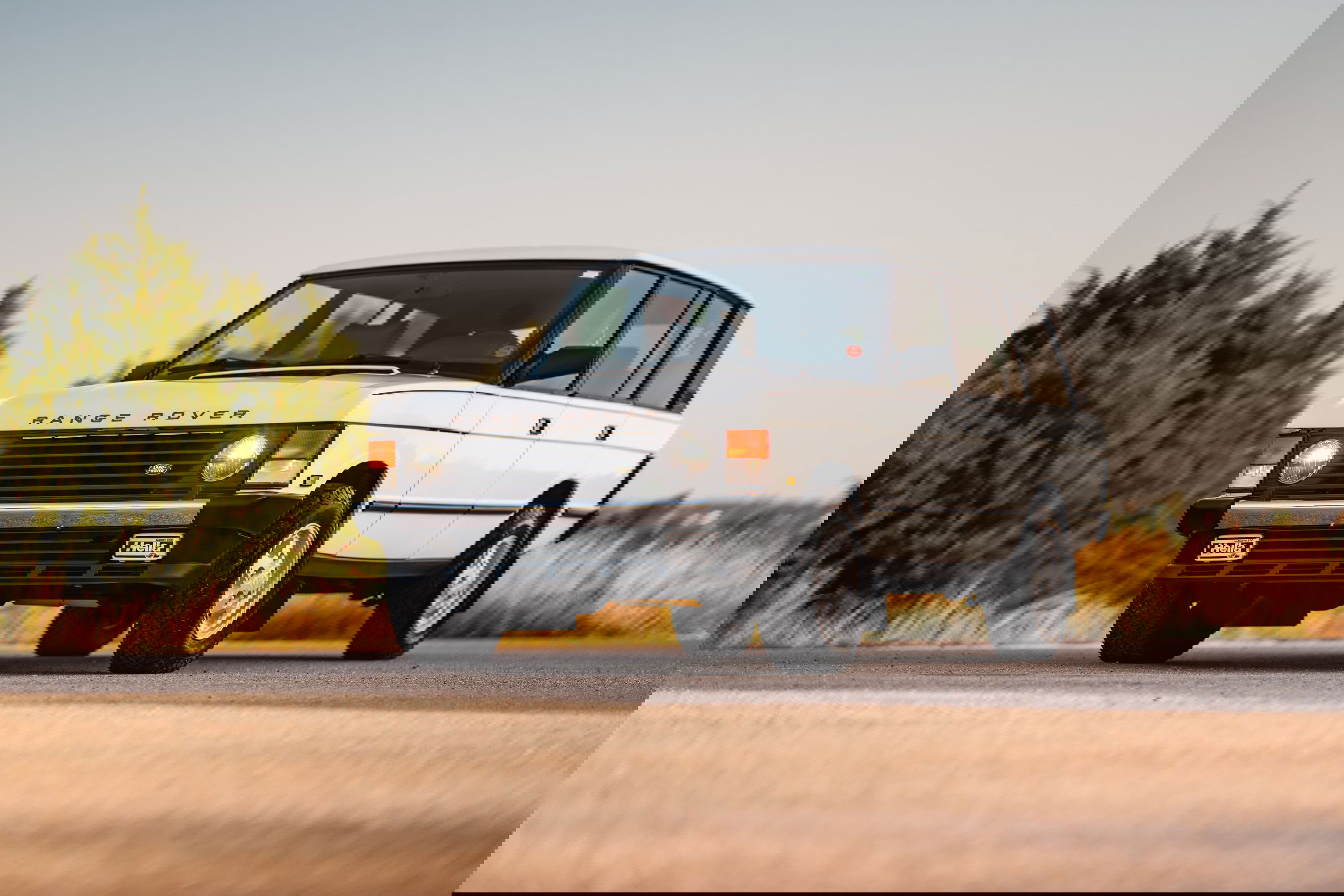 White 1995 Land Rover Range Rover County on road with trees.