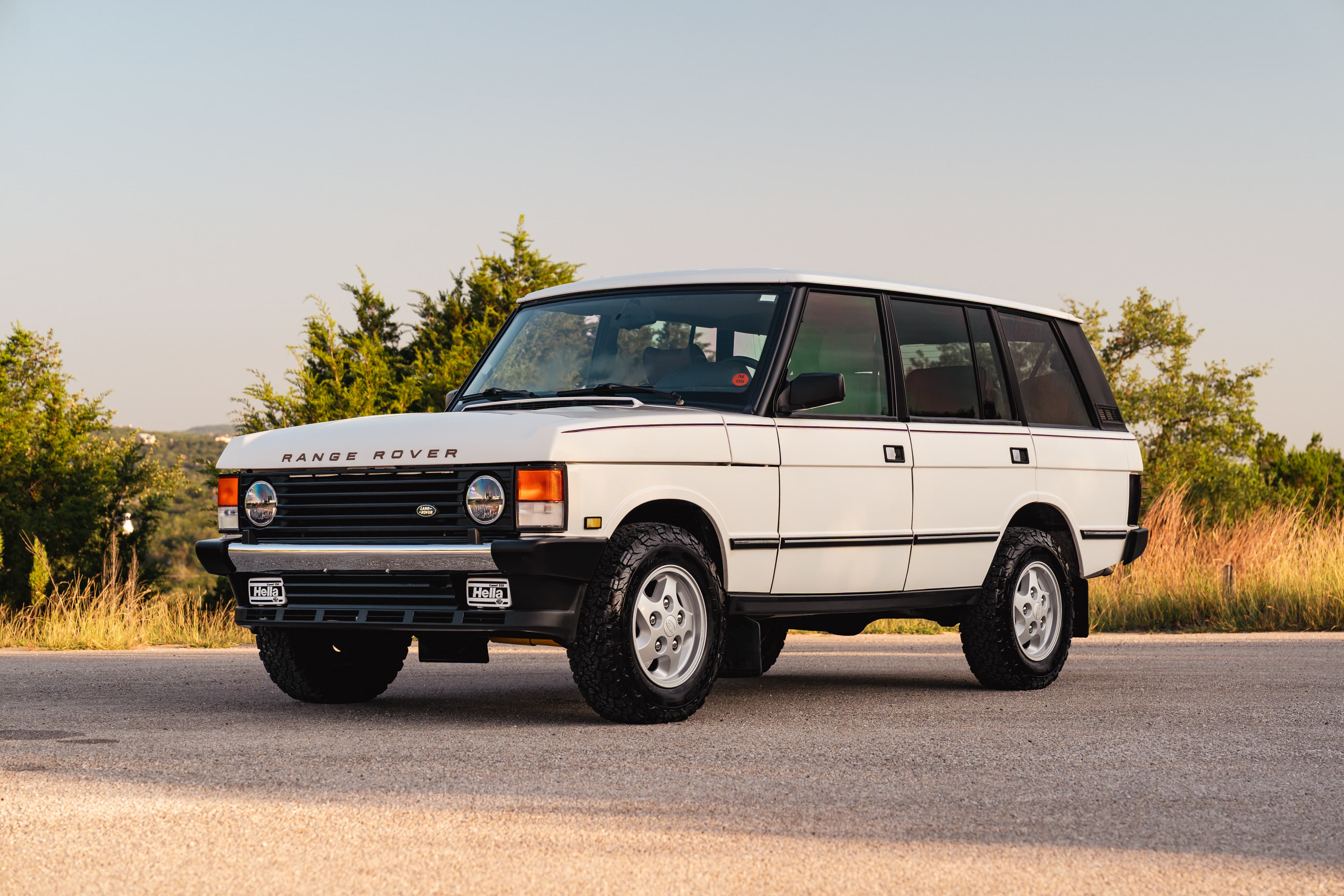 White 1995 Range Rover County edition with chrome accents and classic alloy rims.