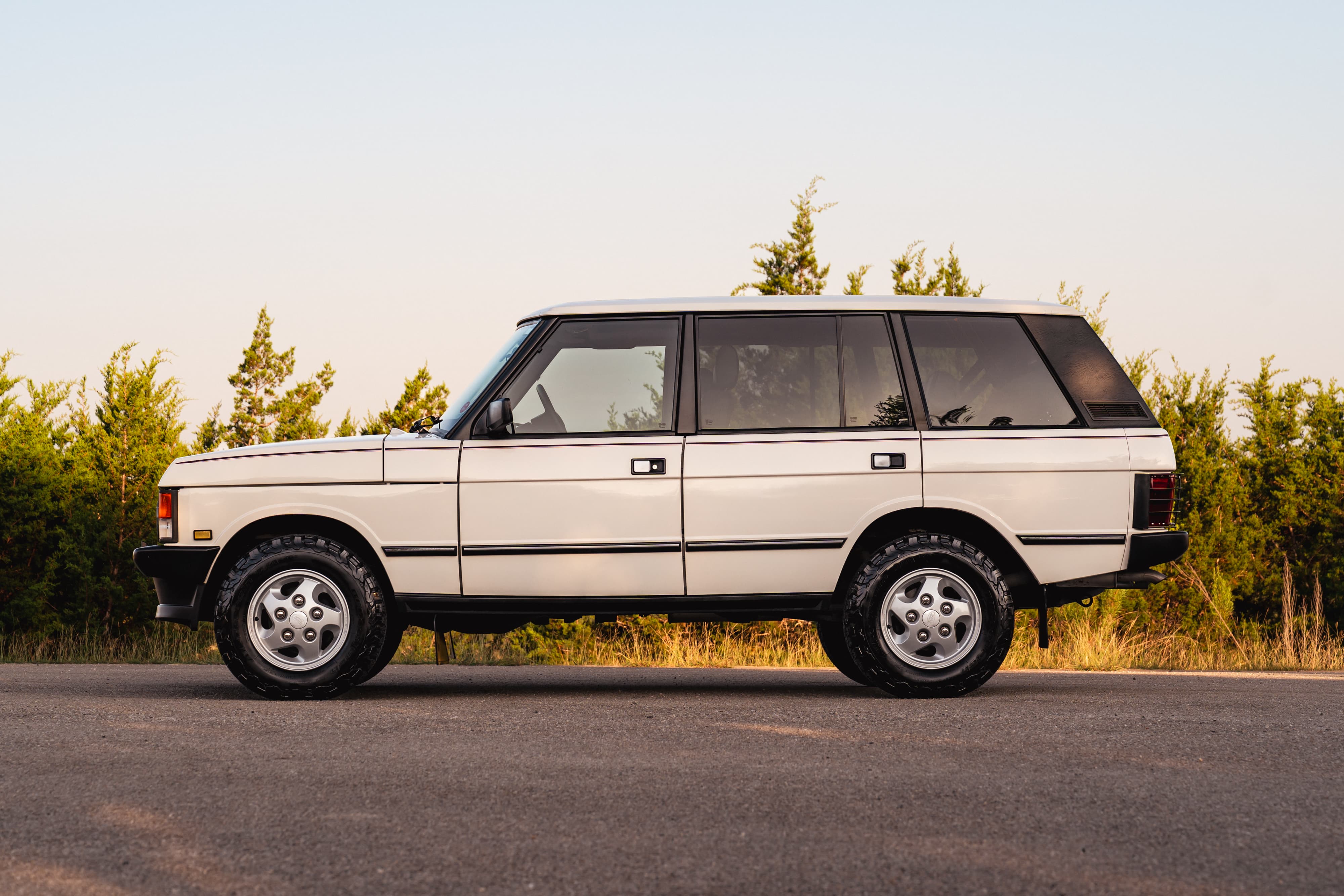 Side profile of a white 1995 Range Rover County with chrome trim and five-spoke alloy rims.