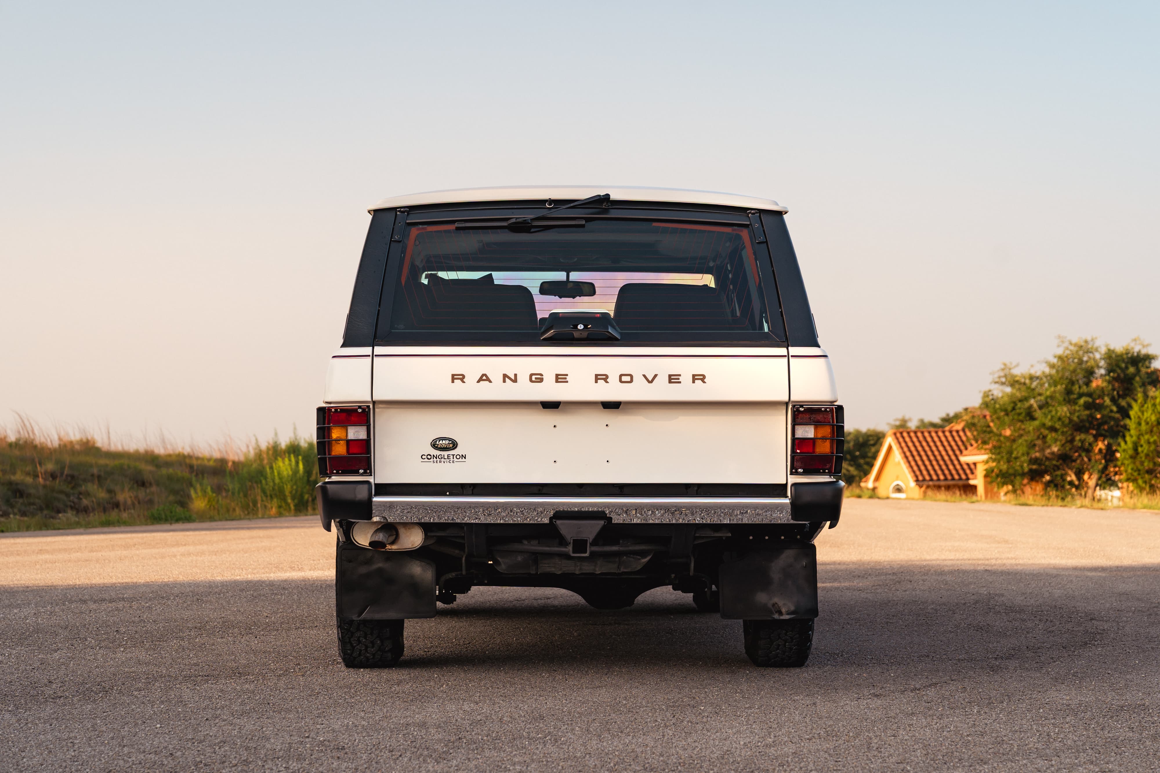 Rear view of a white 1995 Range Rover County with mud flaps and rugged rims.