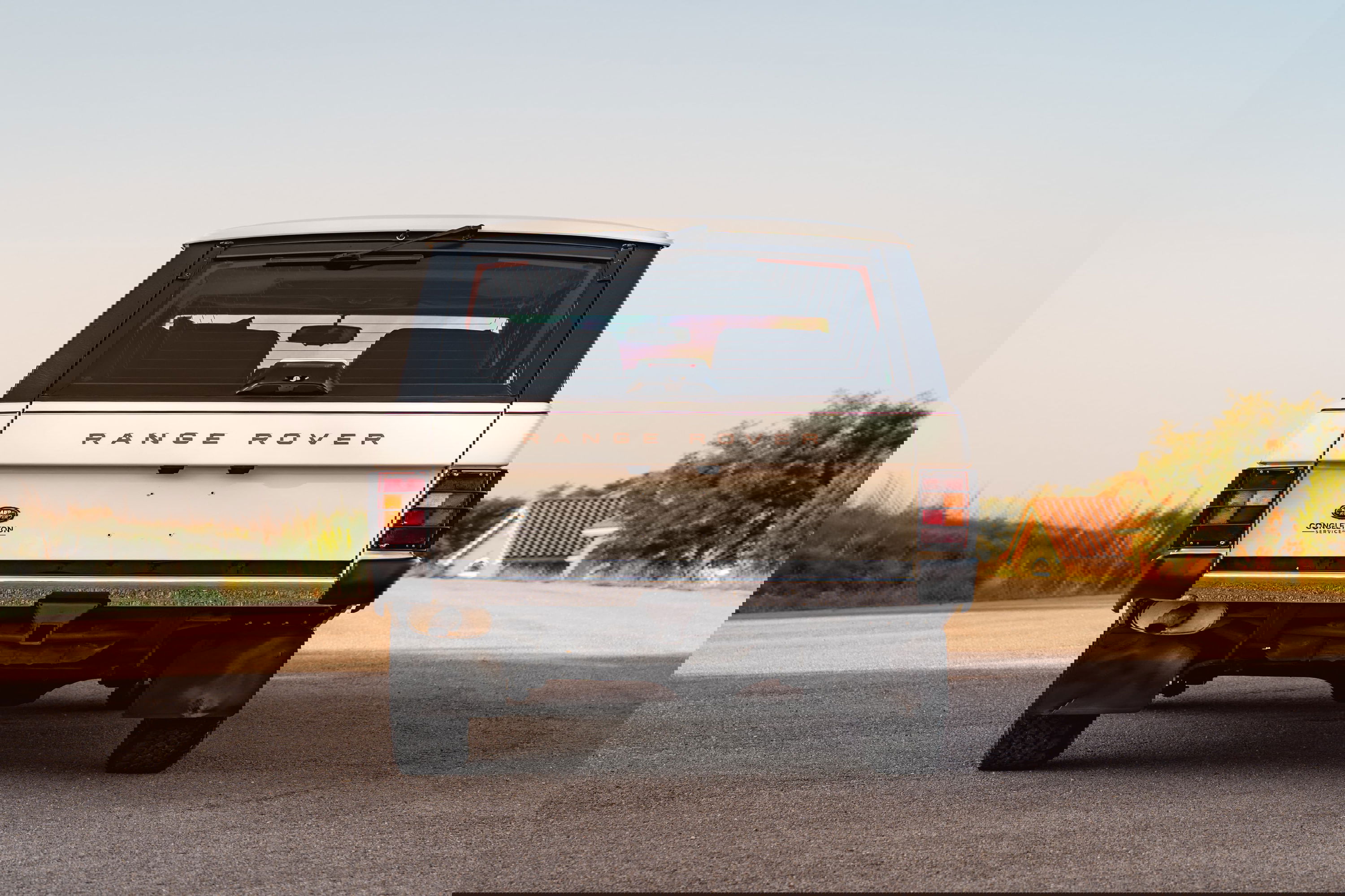 Rear view of a white 1995 Range Rover County with mud flaps and rugged rims.