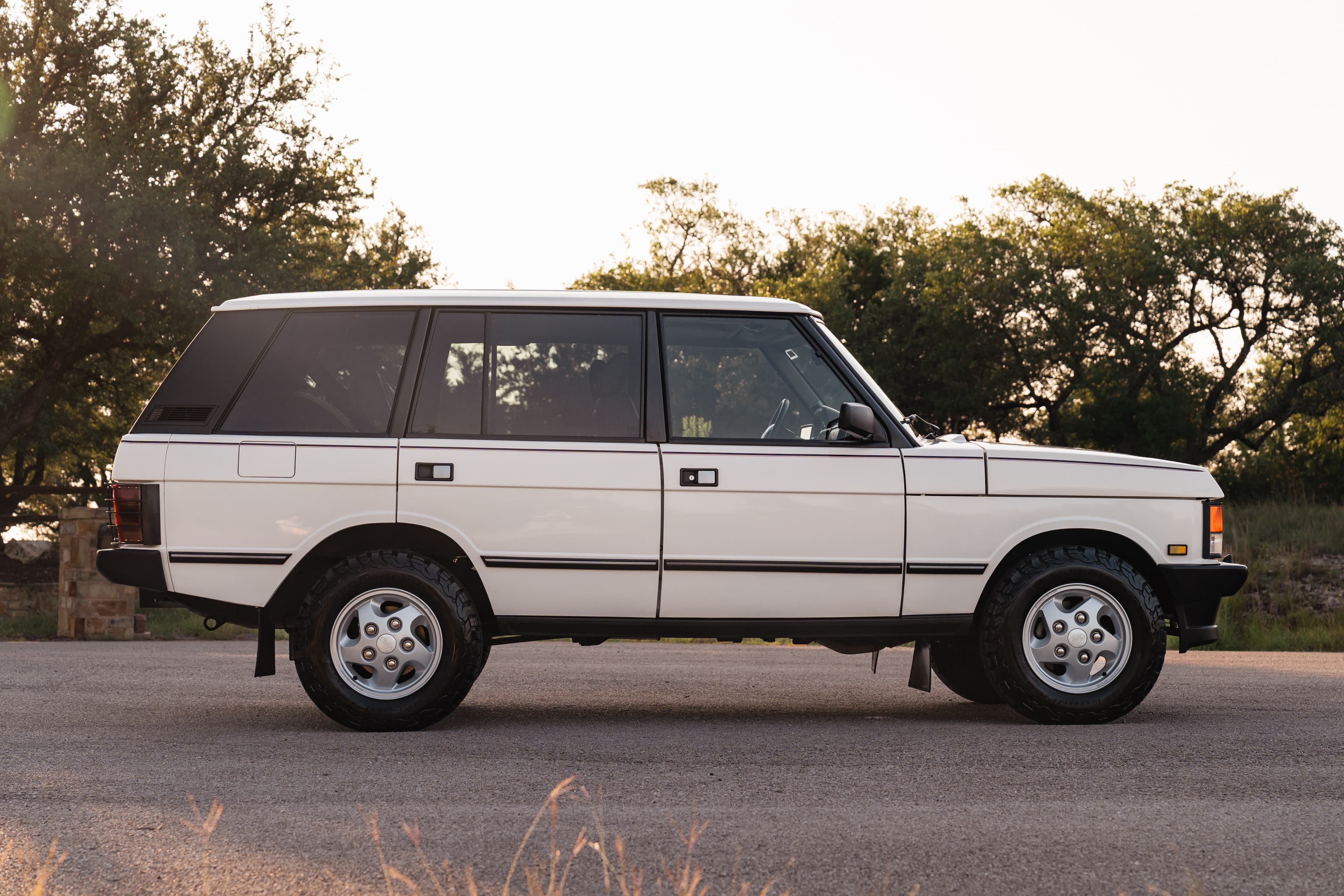 Side profile of a white 1995 Land Rover Range Rover County with silver five-spoke rims.