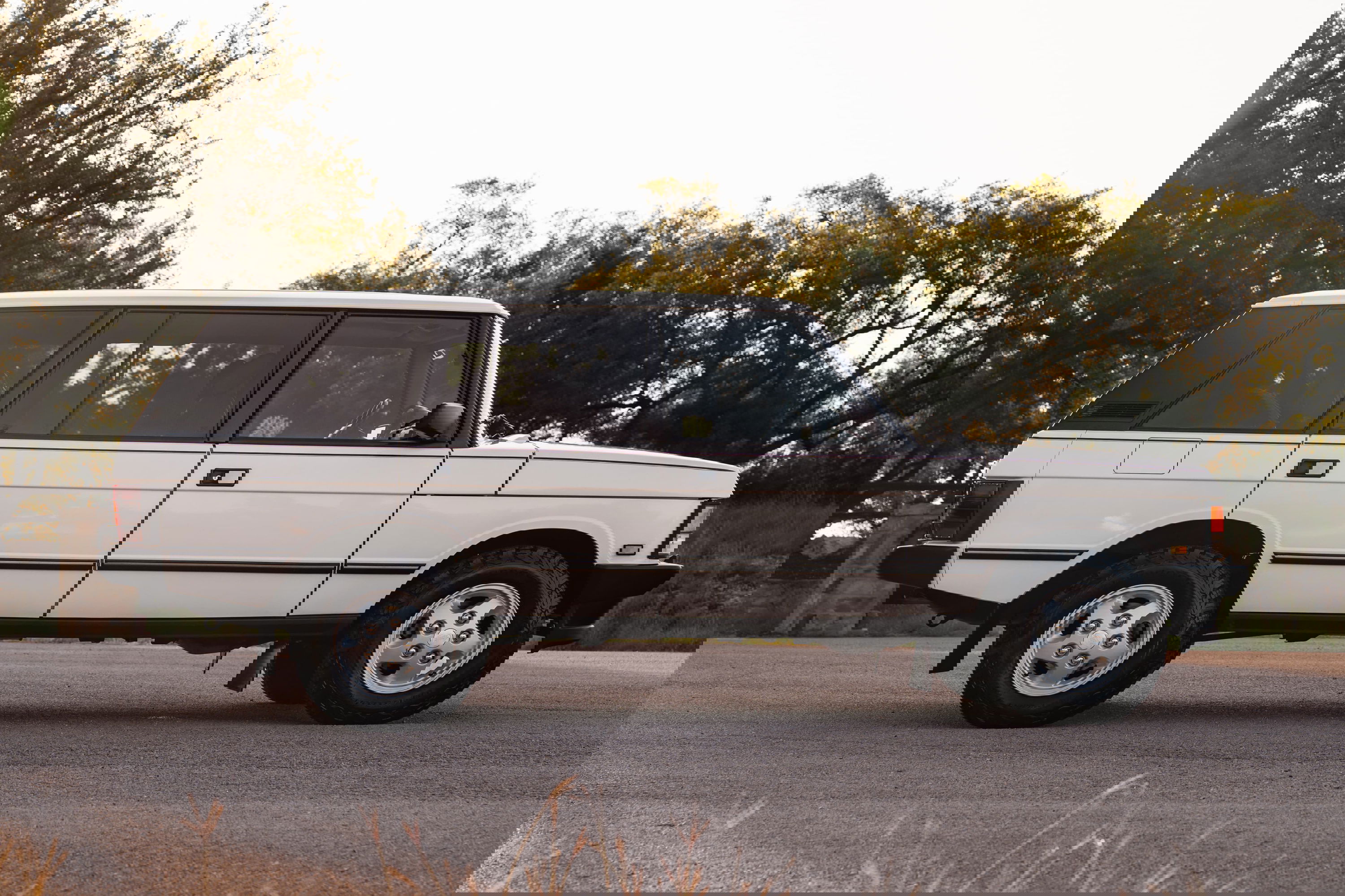 Side profile of a white 1995 Land Rover Range Rover County with silver five-spoke rims.