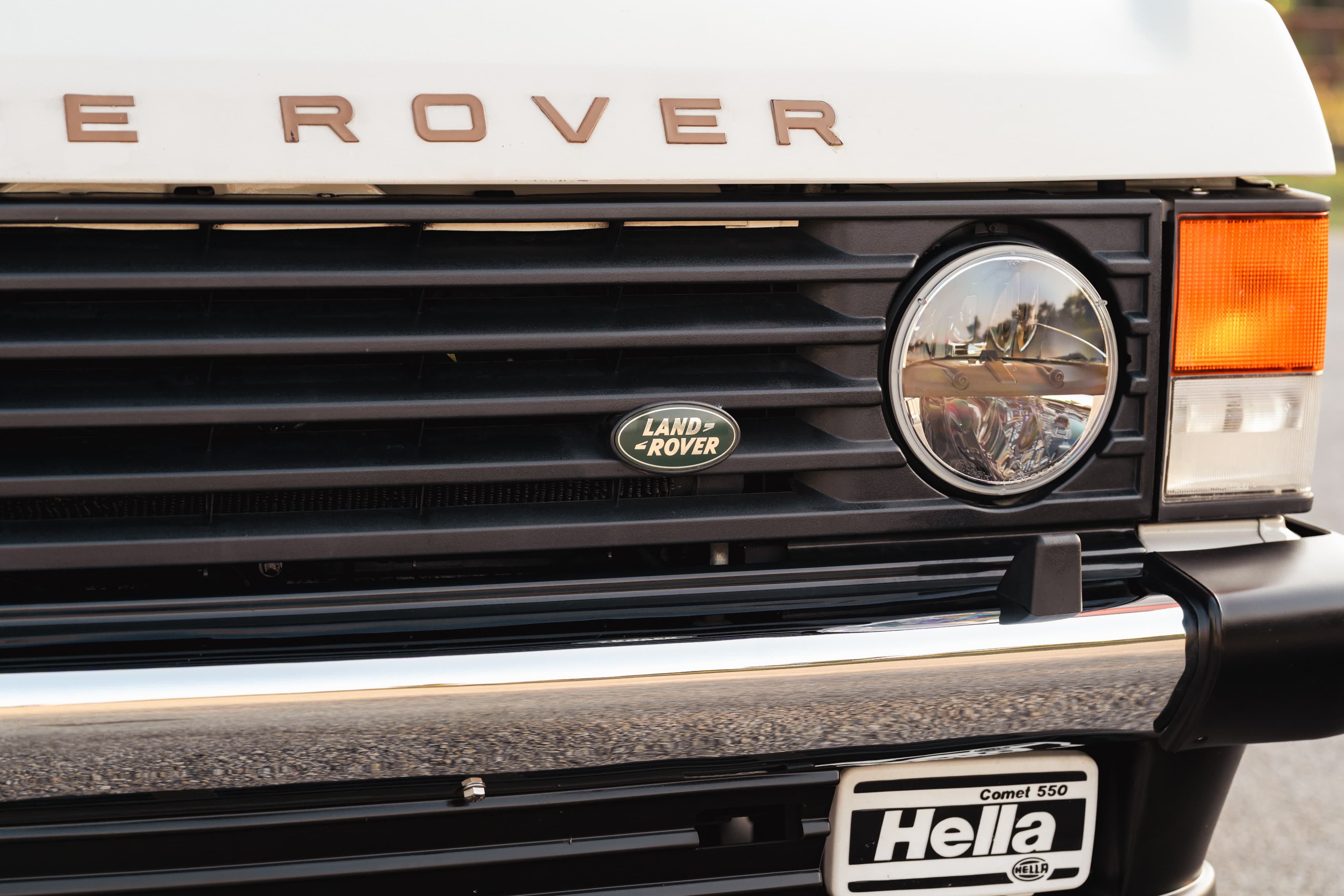 Close-up of a white 1995 Land Rover Range Rover County grille, featuring round headlights and a chrome bumper.
